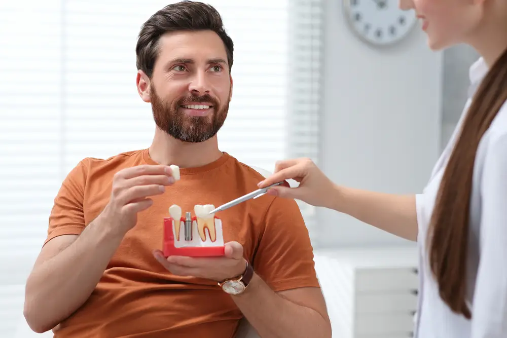 young man sitting with doctor learning about dental crowns