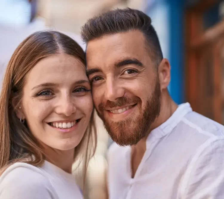 young couple wearing white and smiling happily together