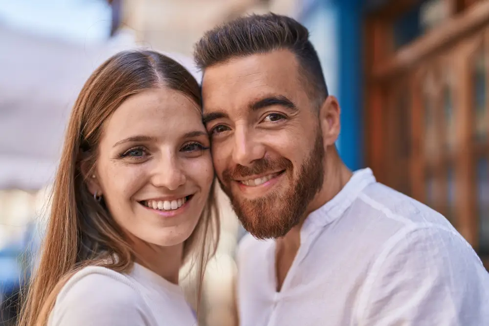 young couple wearing white and smiling happily together