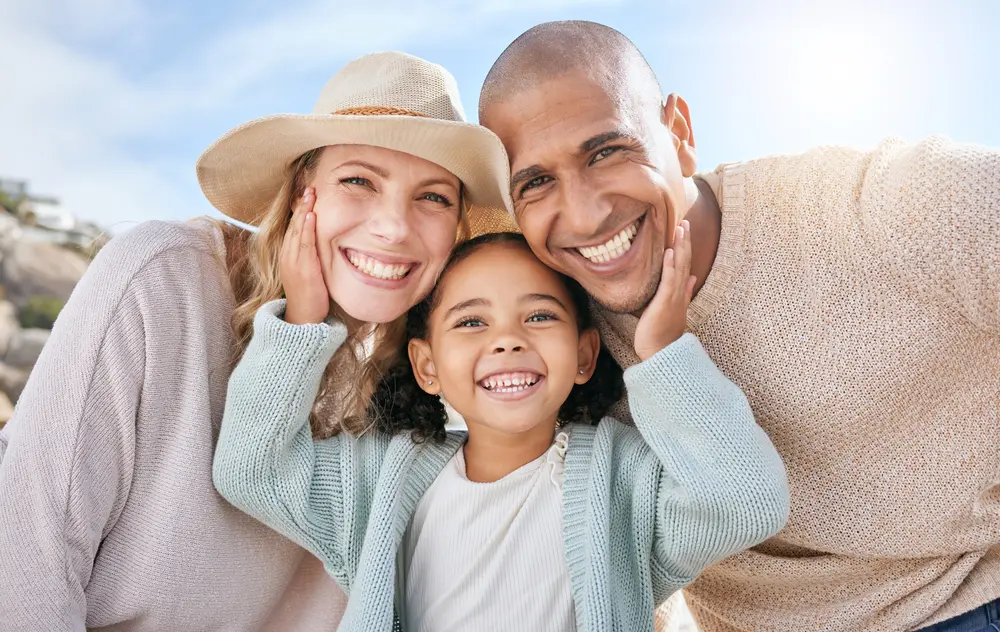 family of 3 smiling happily together